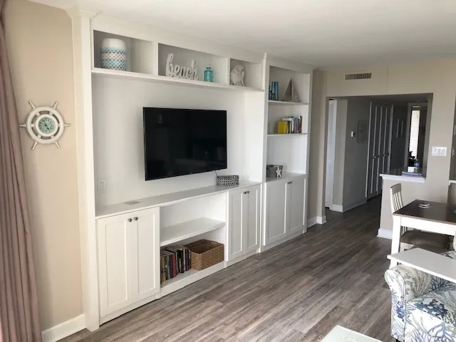 Custom white entertainment center with a wall-mounted TV, open shelves, coastal decor and lower shaker cabinets